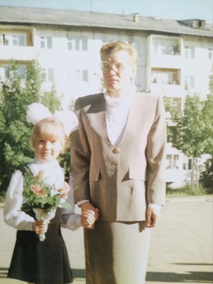 Мама ведёт меня в первый класс. В букете, кажется, мелкие розочки и аспарагус.