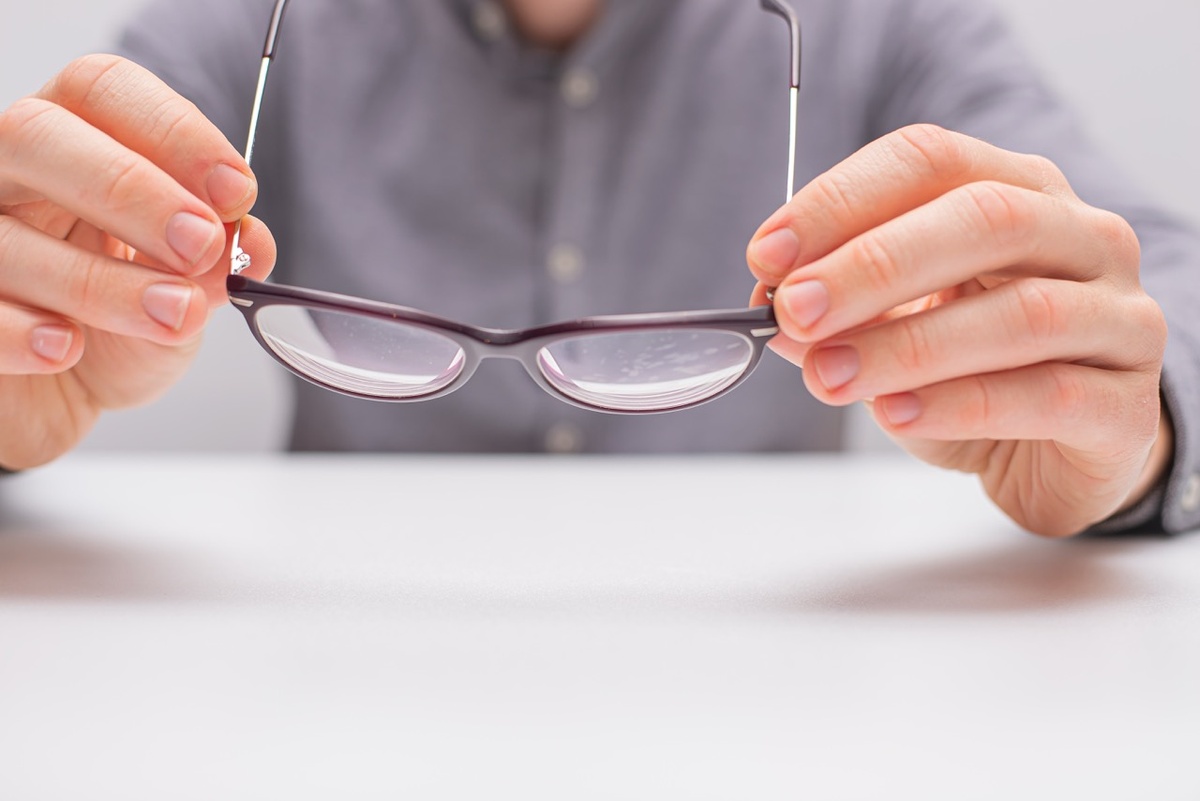 Мужчина держит очки