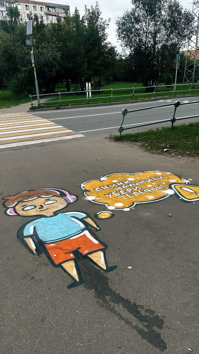 Здорово придумали нарисовать мальчишку в наушниках у пешеходного перехода. Многие дети бредут в школу, уткнувшись в телефон, что опасно, а здесь такое яркое напоминание.
