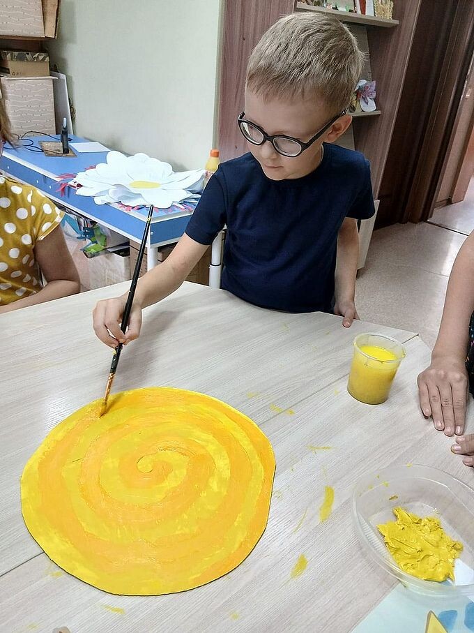 Мальчик раскрашивает кистью «Фанерное солнце»