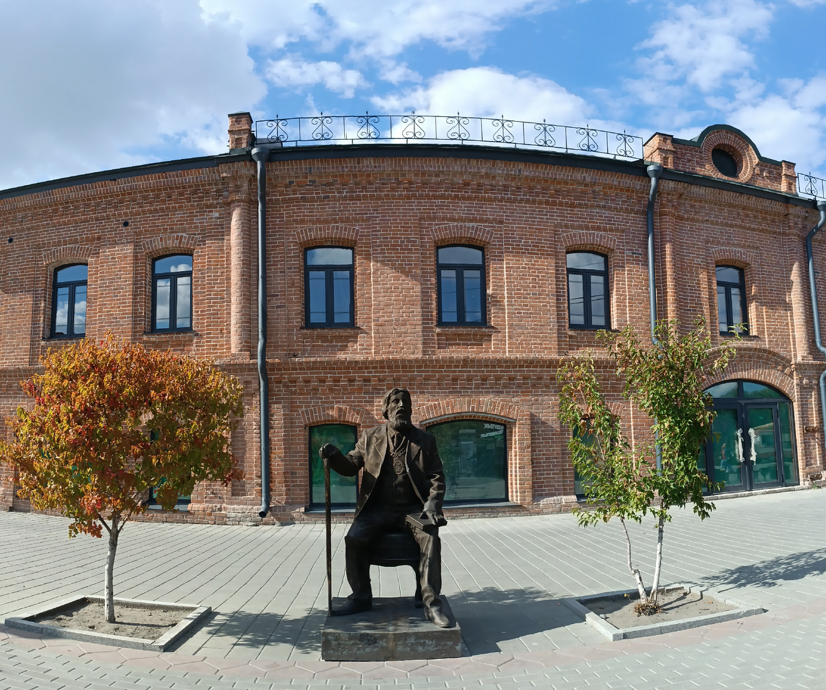 Памятник бывшему городовому. На заднем фоне торговый дом Поскотинова, который в данный момент реставрируется. Где-то на просторах моего города. Фотография автора, сентябрь 2025 года. 