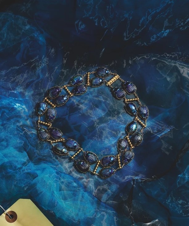 Миа Гот носит ожерелье Tiffany & Co. Archive Favrile Glass Scarab в фильме «Франкенштейн». (Tiffany & Co.)