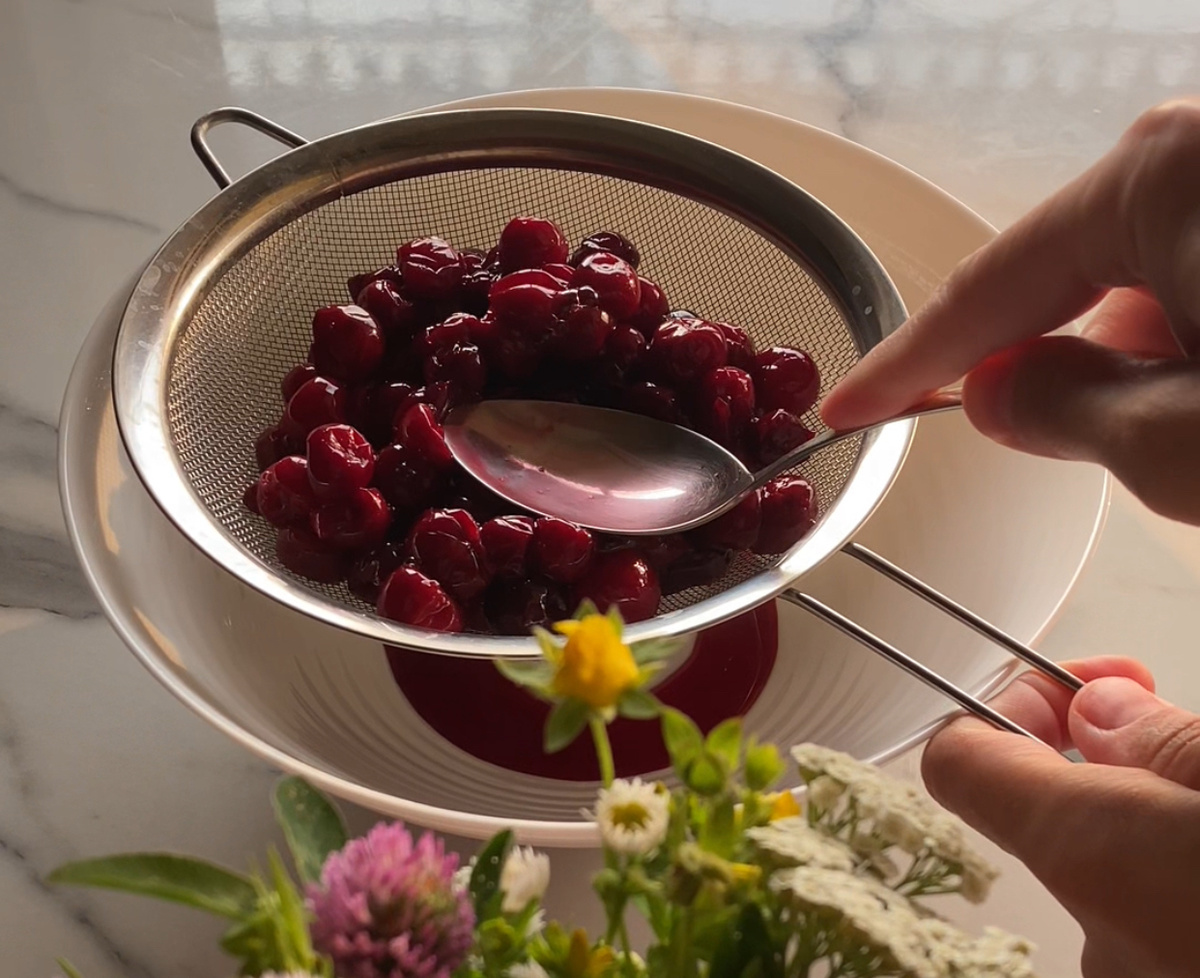 Положить размороженную вишню на сито, чтобы стек лишний сок.