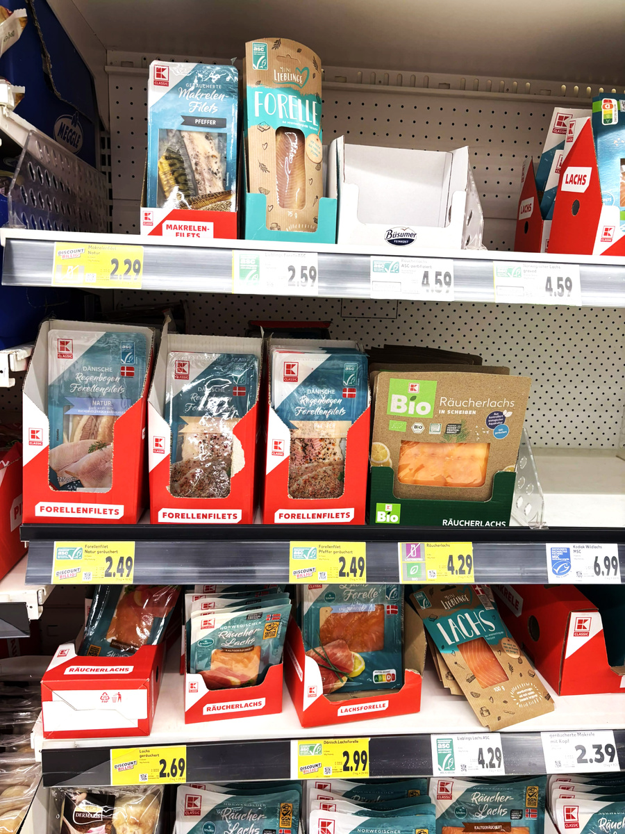 Витрина мегамаркета, в магазинах поменьше выбор скуден. На верхней полке скумбрия и речная форель горячего копчения, на средней - радужная форель горячего копчения и лосось холодного копчения, на нижней - лосось холодного копчения. Фото автора.
