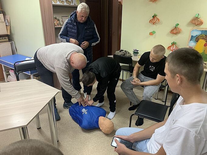 Инструктор показывает подростку расположение солнечного сплетения на манекене