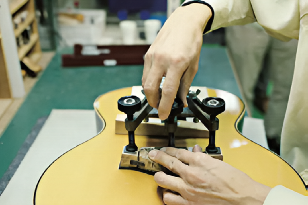 Установка подставки гитары при помощи специального инструмента на производстве Yamaha