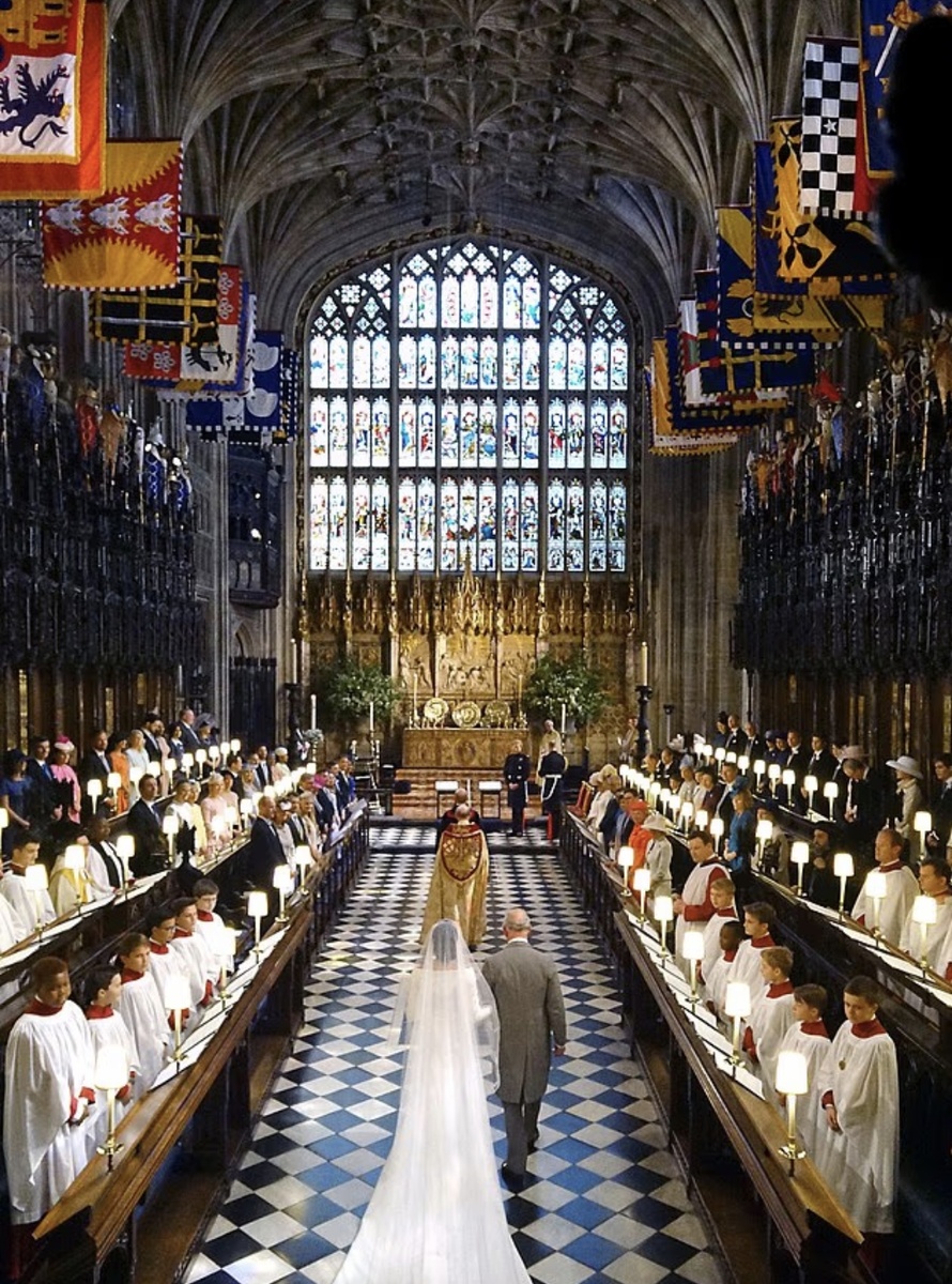 Чарльз опубликовал заявление, в котором заявил, что он «рад приветствовать её в королевской семье таким образом». На фото: принц Уэльский ведёт Меган Маркл к алтарю на её свадьбе с принцем Гарри 19 мая 2018 года.