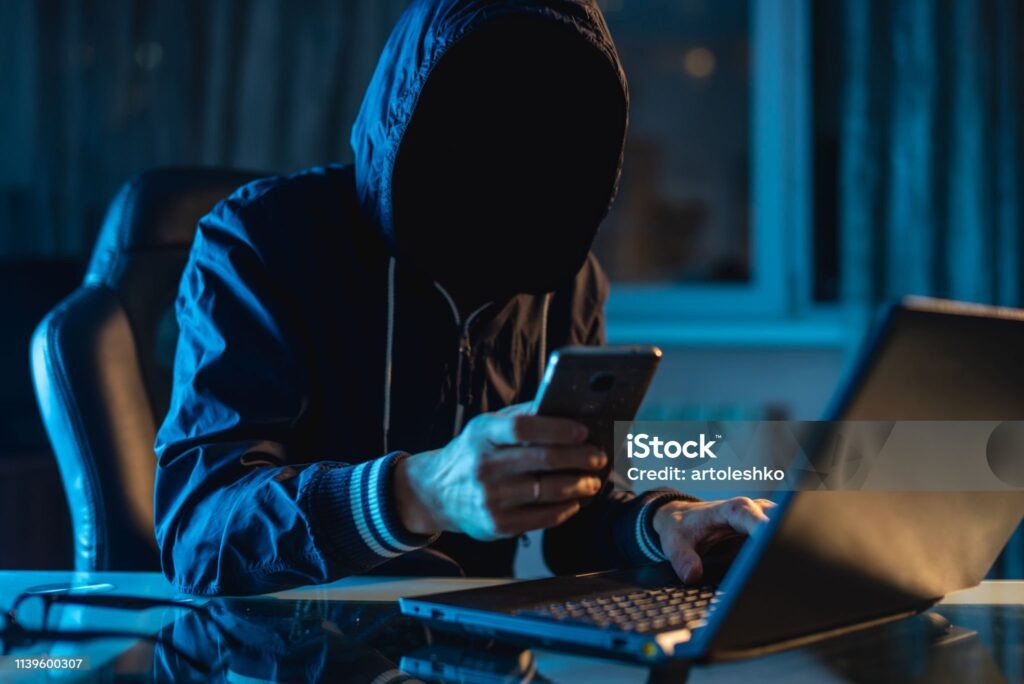    Anonymous hacker programmer uses a laptop to hack the system in the dark. Creation and infection of malicious virus. The concept of cybercrime and hacking database Редакция газеты