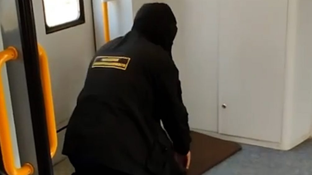   Охранник-мигрант делает намаз прямо на входе в вагон электрички. Фото: кадр видео