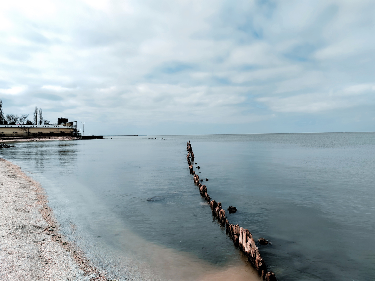Море на Молодежном пляже в городе Ейск с остатками деревянных береговых укреплений в воде. Фото автора
