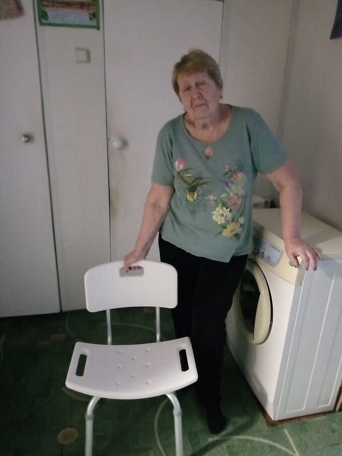 Пожилая женщина держится за табурет для ванной