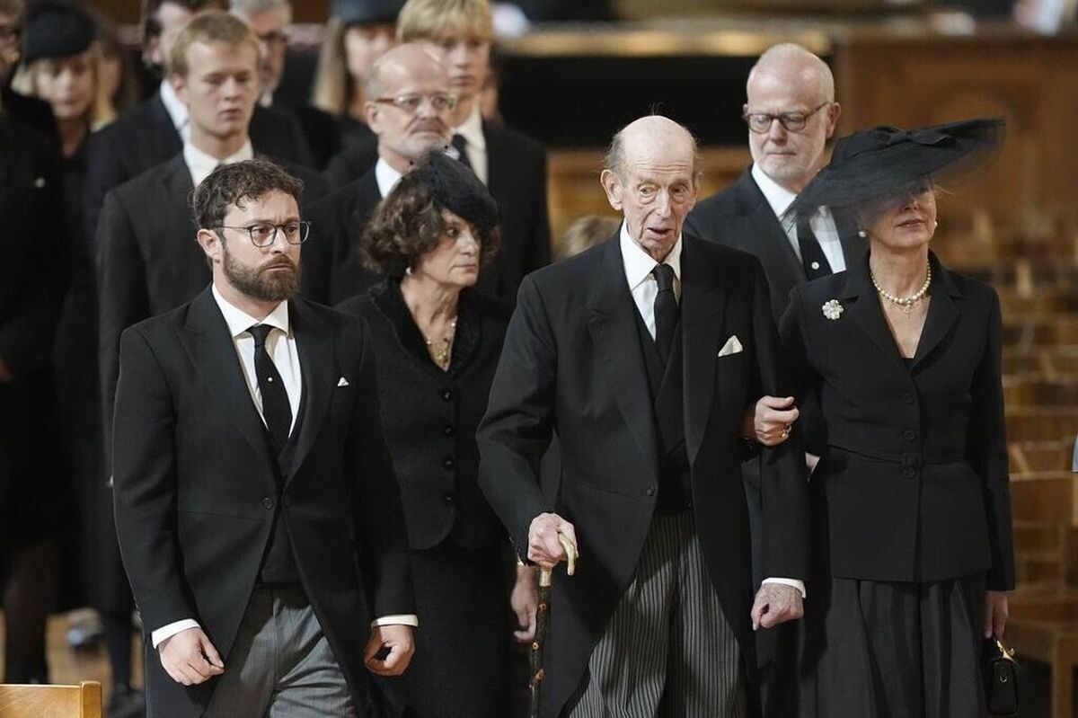 В то время, как герцога Кентского ведет его дочь Хелен, за ним идут  справа налево его старший сын Джордж, граф Сент-Эндрюсский, жена и внук Эдди, лорд Даунпатрик, следующие в очерени на получения титула герцога Кентского. 