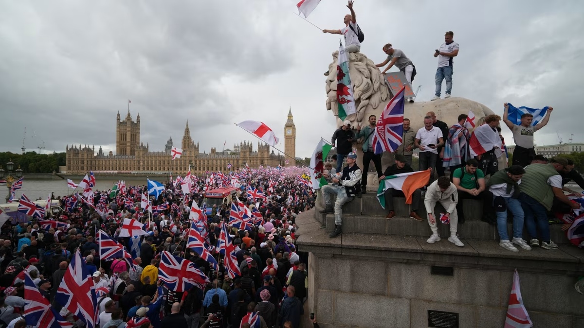 Протестующие размахивают флагами Англии и британскими национальными флагами на Вестминстерском мосту у здания парламента Великобритании во время проведения крупнейшей за последние десятилетия акции протеста "Объединим королевство"*, Лондон, 13.09.2025 г. ©Christopher Furlong/Getty Images