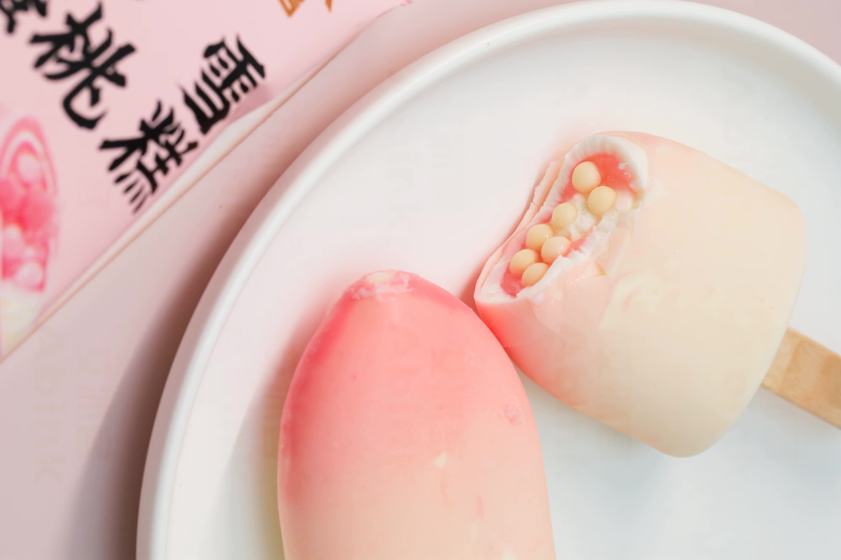 Китайский Abink / Xiao Ai Peach Ice Cream Stick Crispy Chocolate использует белые шоколадные шарики с фруктовой начинкой — визуально эффектно и неожиданно по текстуре.