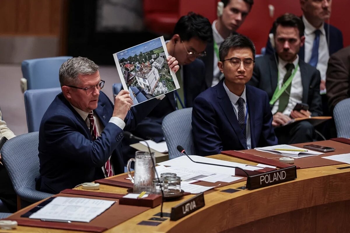    Государственный секретарь Польши Марчин Босацкий держит в руках фотографию во время заседания Совета Безопасности, посвященного угрозам международному миру и безопасности. Штаб-квартира ООН в Нью-Йорке.