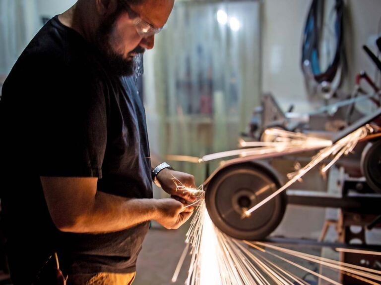 Алекс Харрисон, член гильдии ножеделов, затачивает лезвие в своей мастерской.