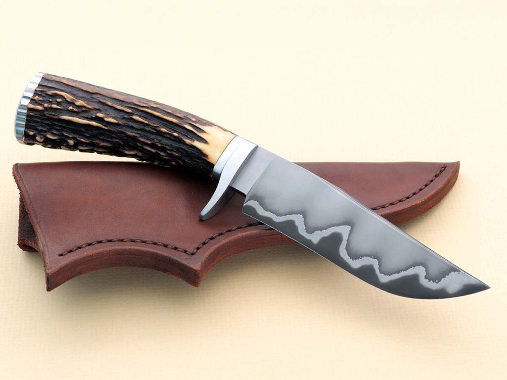 Производитель: Wess Barnhill
Модель: Drop-point hunter
Длина клинка: 5 дюймов
Материал клинка: San-mai из углеродистой стали 1075 и нержавеющей стали 410
Гарда и торец: Нержавеющая сталь
Материал рукояти: Sambar stag
Общая длина: 9,75 дюйма
Ножны: Эксклюзивные кожаные ножны, изготовленные на заказ Уэссом Барнхиллом.