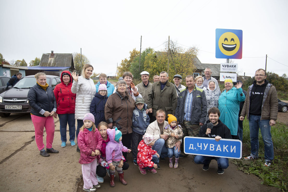 Жители деревни на фоне въезда в поселение