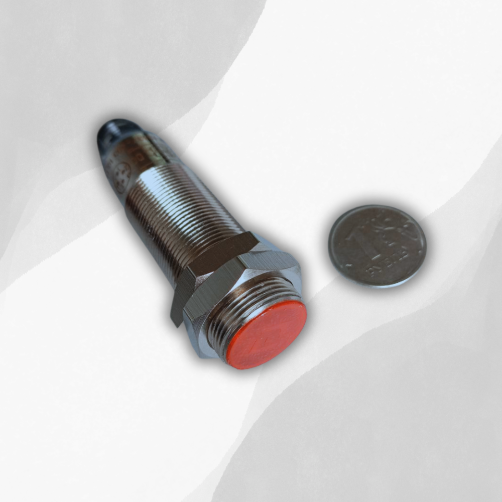 Датчик в сравнении с монетой. Диаметр датчика М18