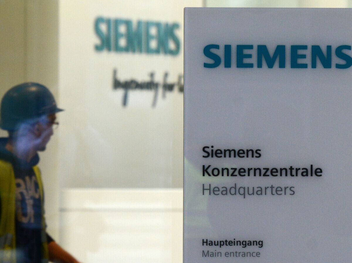    # Рабочий у входа в штаб-квартиру компании Siemens в Мюнхене, Германия© AFP / Christoph Stache