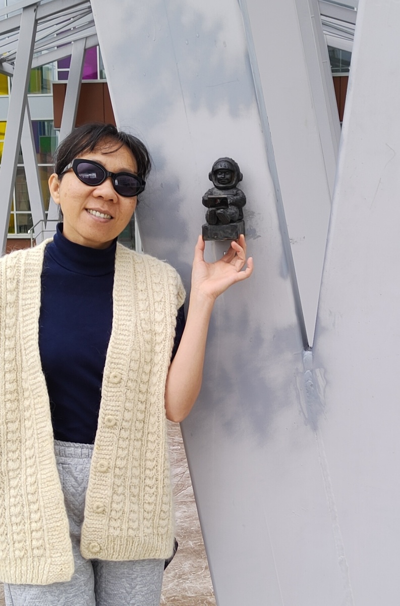 Сидит с ноутбуком.