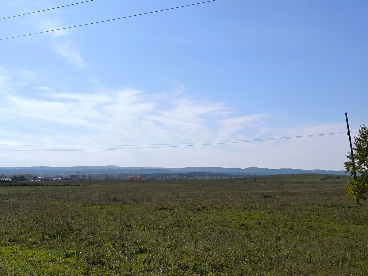 На въезде с запада. Вдали виднеется двухвершинная гора Копна. До неё отсюда 15 километров и она уже в Гурьевском районе