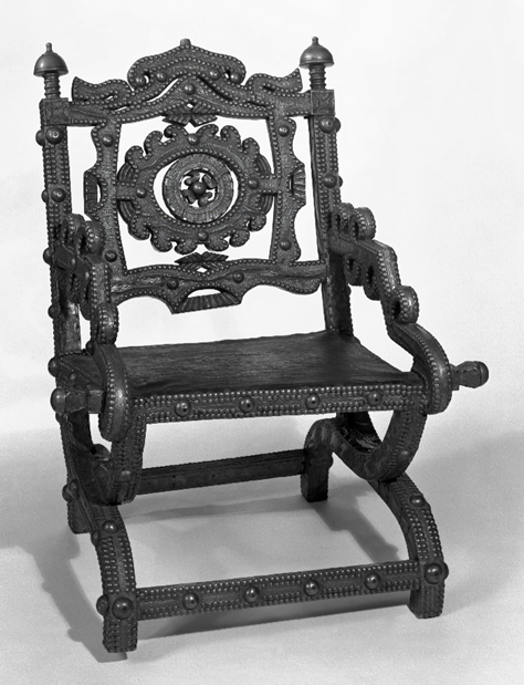 Кресло Аконкромфи. Каркас стула вырезан из дерева и, за исключением кожаного сиденья, полностью покрыт листовой латунью. Листовая латунь украшена различными штампованными и насечками. Латунные гвозди расположены в два ряда по краям каркаса, покрытого листовой латунью. На раме через равные промежутки прикреплены рельефные латунные полусферические элементы. Нижняя сторона кожаного сиденья выполнена в виде кожаной решетки. Ножки выполнены в форме буквы "х" и изящно изгибаются наружу.