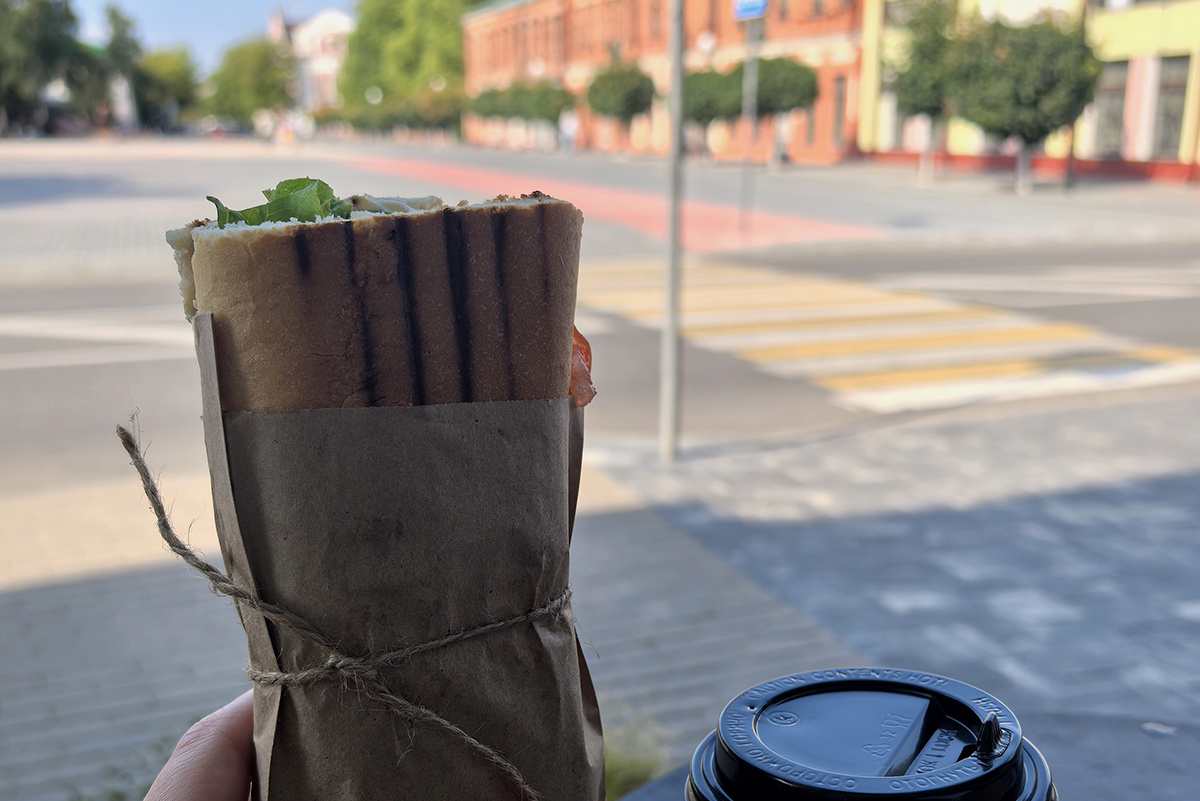 Все сложилось: прекрасный вид на центральную улицу, эстетичная упаковка и вкусный горячий бутерброд (французский багет, тунец, кукуруза, помидор, салат, соус). 