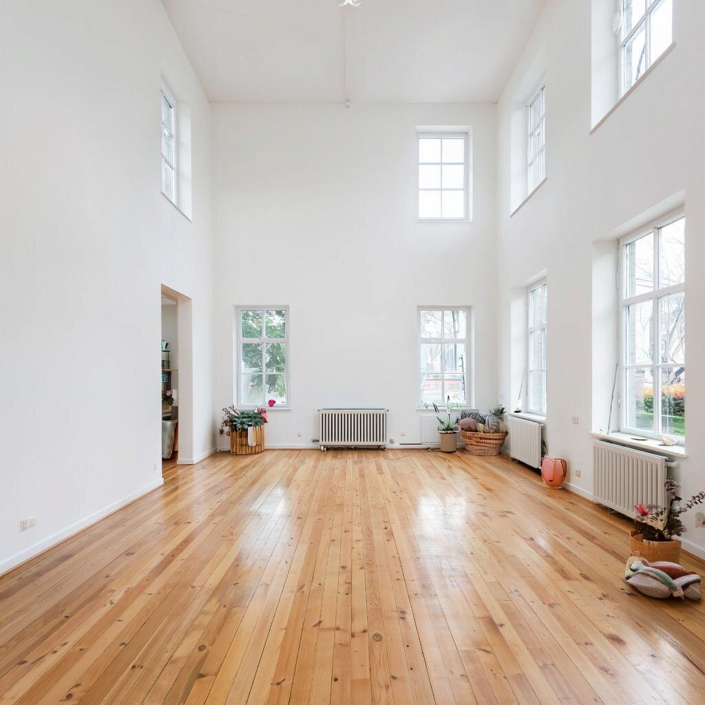 Просторная гостиная в скандинавском стиле с белыми стенами и потолком, деревянным полом и минимальным декором.