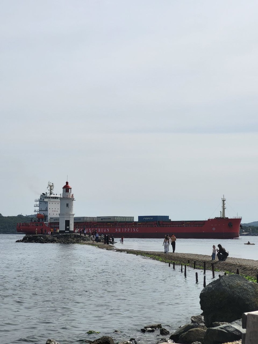 Маяк Токарёвского на фоне проходящего китайского сухогруза