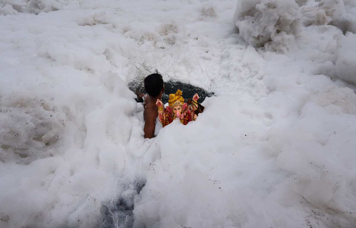 Делиец погружает статую бога Ганеши в Ямуну в дни празднования фестиваля Ганеша-Чатуртхи в Нью-Дели. Фото: Shutterstock