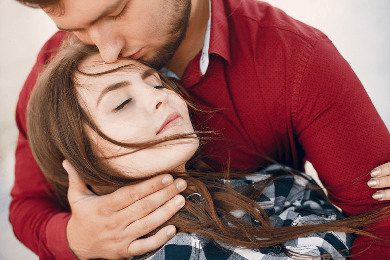 Мужчина целует девушку в голову, выражая заботу и нежность в отношениях