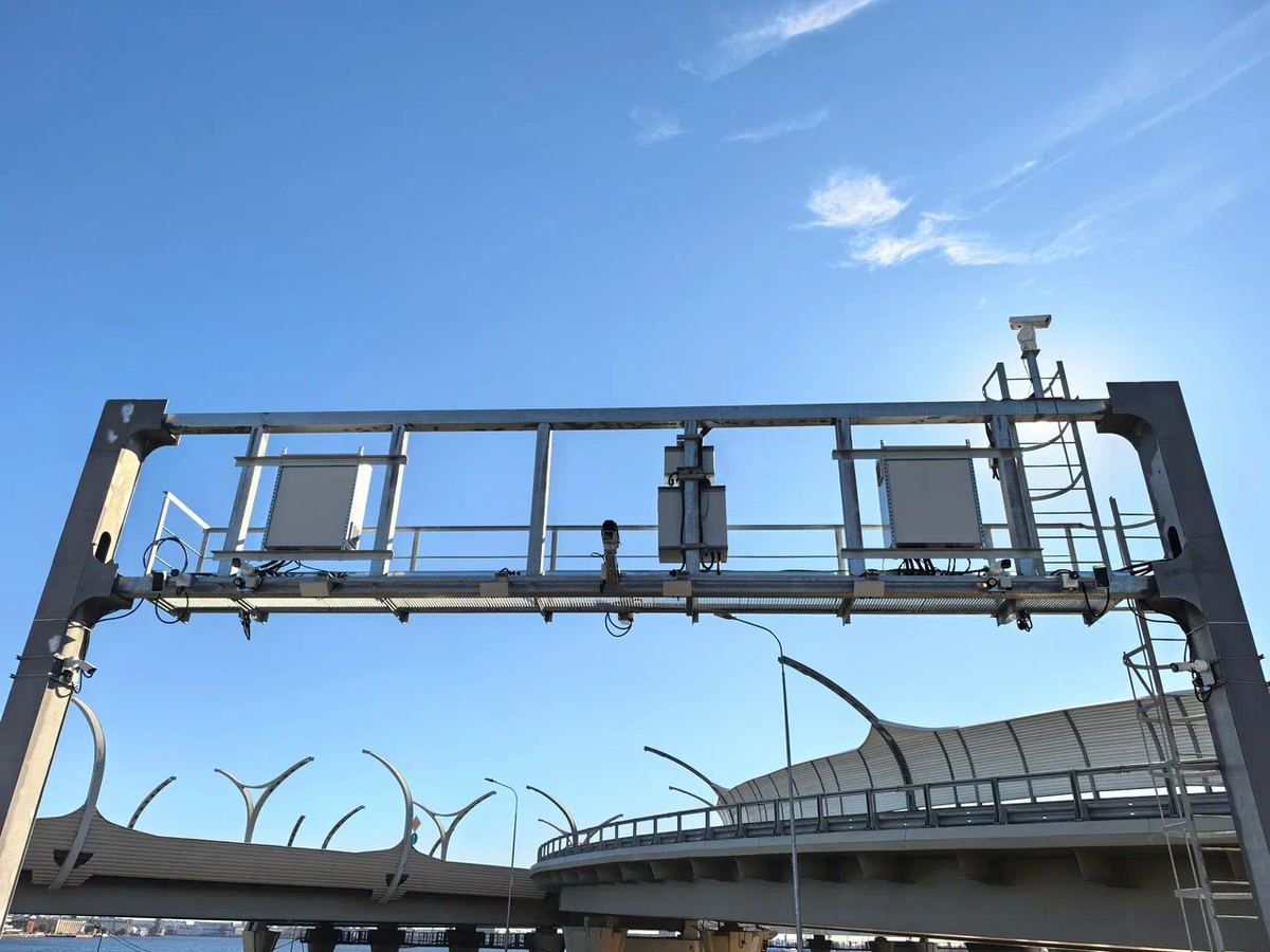 Белые панельные антенны - для считывания транспондеров, камеры по краям - для определения габаритов машин и считывания номеров, чёрные панели - ИК-подсветка, по центру камера наблюдения. В шкафах - компьютеры и оборудование для поддержания постоянной температуры и влажности.