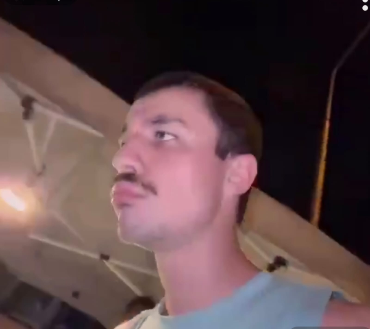 Россиянин Гриша Дзегкоев (скан с видео, где он переворачивает  торговцу стол с сосисками). 