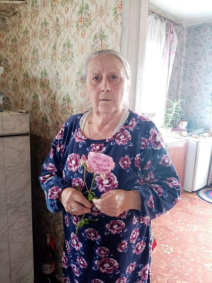 Пожилая женщина с подаренной ей розой