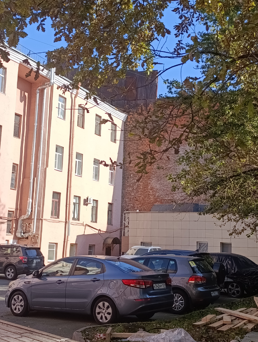 Стена жилого дома слева и красная кирпичная- забор тюрьмы