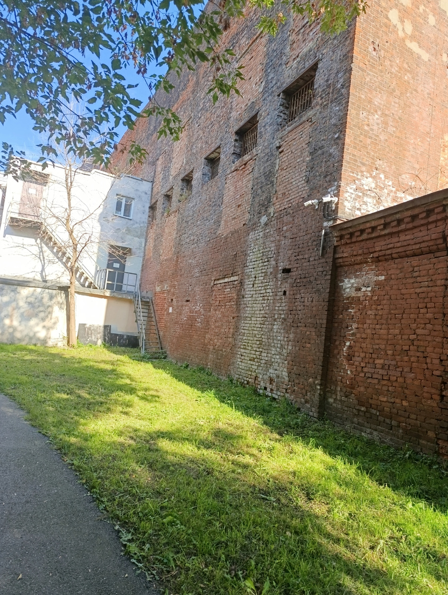 Окна с решётками  напоминают бойницы. Рядом дорожка для прогулок. 