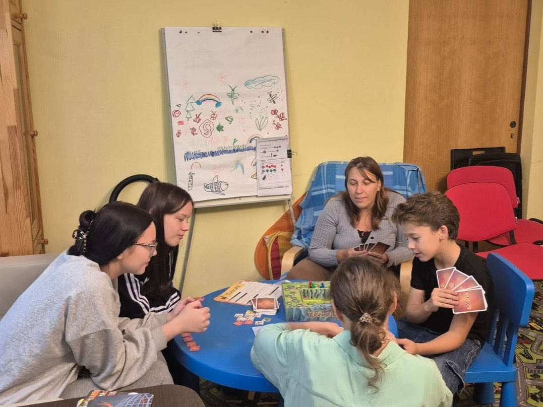 Социальный педагог Детской деревни SOS Томилино Светлана Шарапова играет с детьми в настольную игру «Диксит» 