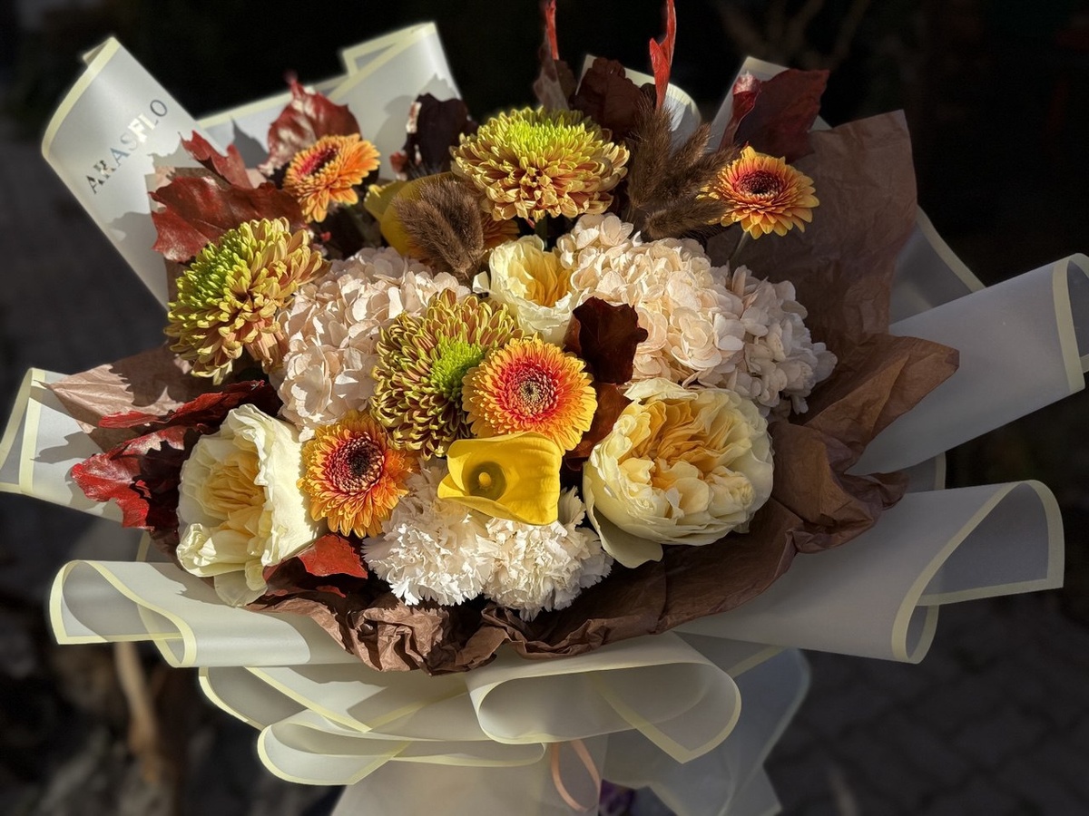 в составе пионовидные розы, герберы, гортензии, шикарного цвета хризантемы, огромные бклые гвоздики и желтые каллы. В обрамлении красные осенние листья - восторг!