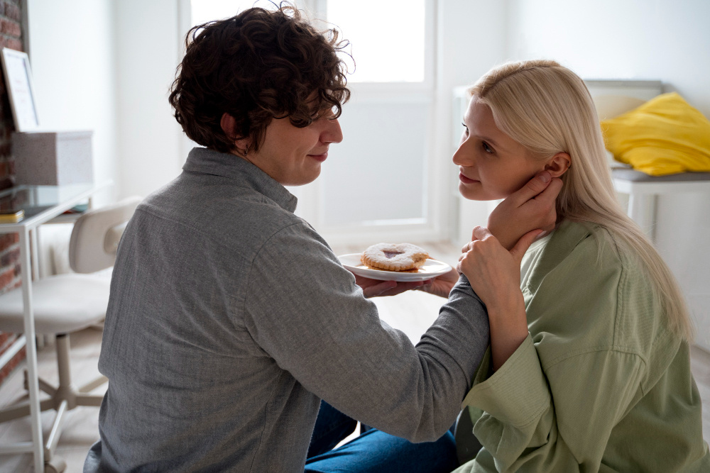 Молодая пара завтракает дома, мужчина нежно держит женщину за щёку — забота, уют и доверие в семье