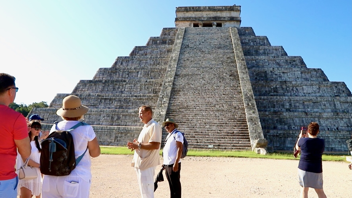 Туристы перед пирамидой Кукулькана. Гид показывает акустический эффект — “поющий камень”