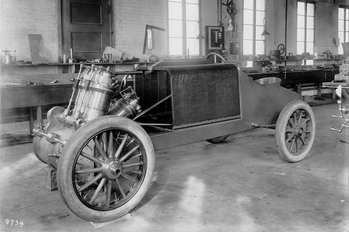 гоночный автомобиль 1907 года с V-образным четырехцилиндровым двигателем во время изготовления на заводе Уолтера Кристи в Нью-Йорке. Приводной вал водяного насоса можно увидеть позади и справа от переднего колеса, он простирается к нижней части радиатора. Этот вал приводился в движение конической зубчатой передачей, видимой перед первым рядом цилиндров