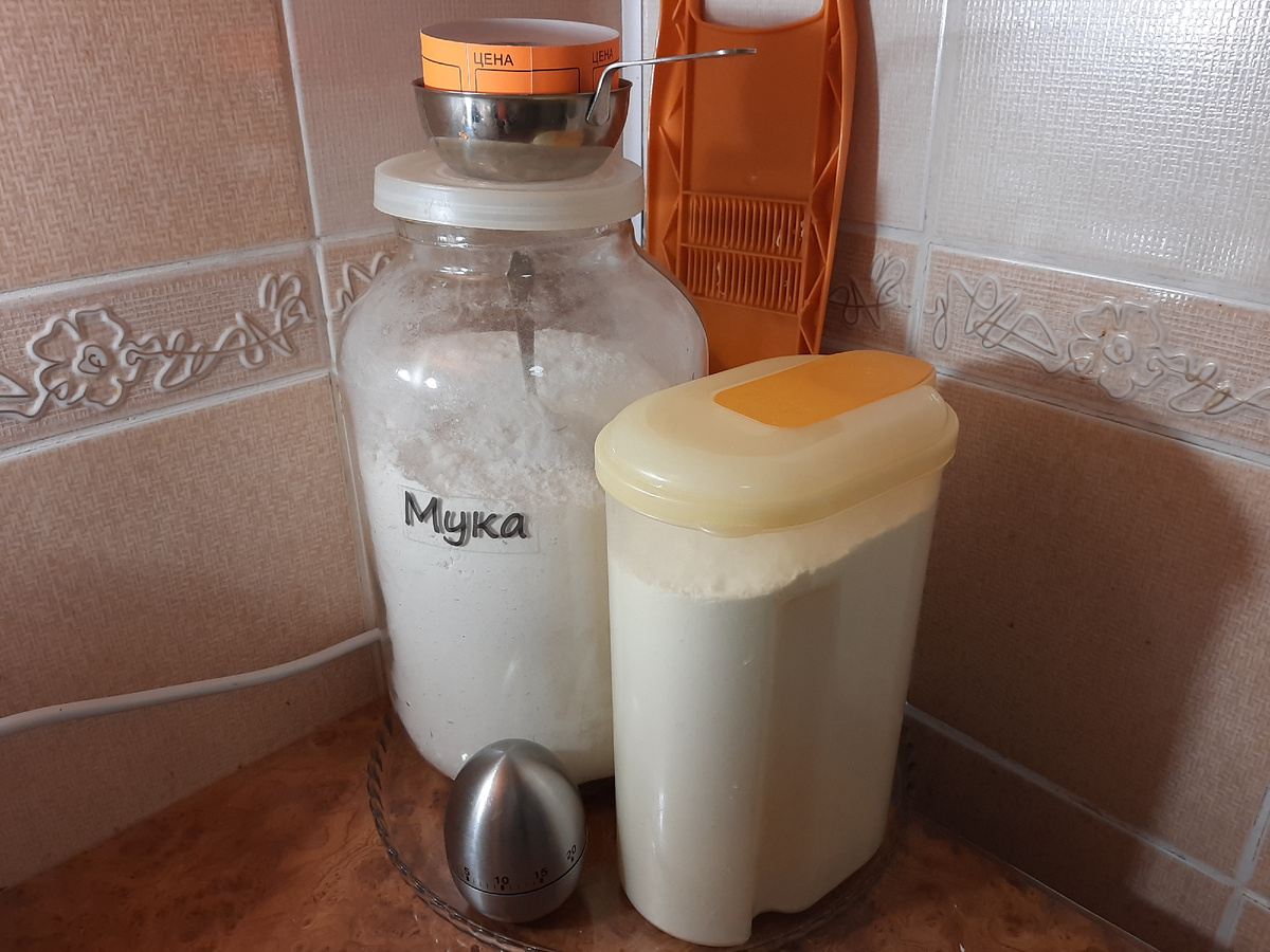 Мука и полутени... вечернее фото. Из-за нехватки места использую каждый сантиметр пространства. Сзади банки, спрятавшись за ней, висит на крючке тёрка. Она под рукой. На банке  в кокотнице находится лента-ценник, использую в качестве ярлыков на пакеты для заморозки. Подписал и наклеил.  