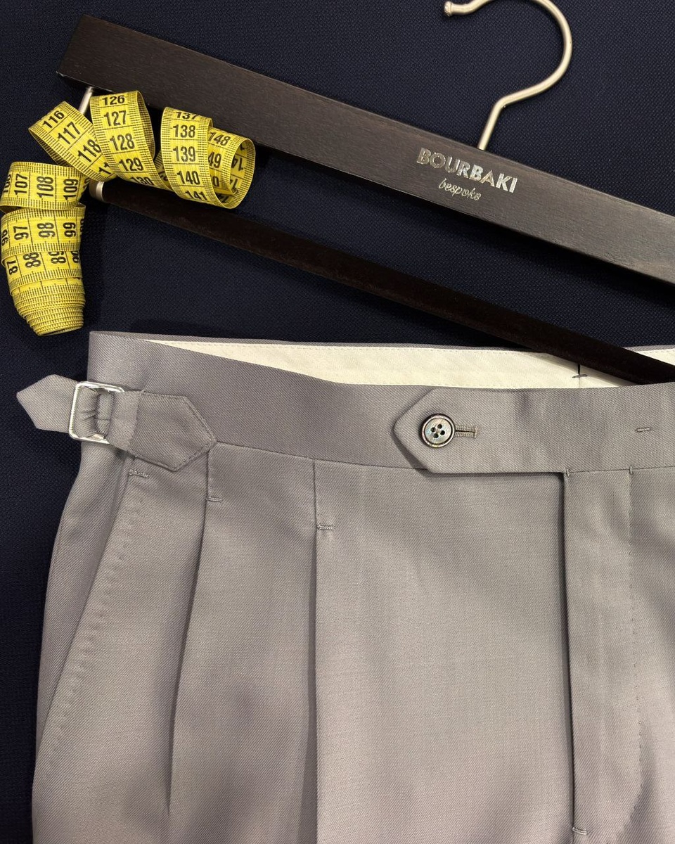 Шерстяные брюки серого цвета с двойными защипами и боковыми регуляторами объема, изготовленные в ателье Bourbaki
