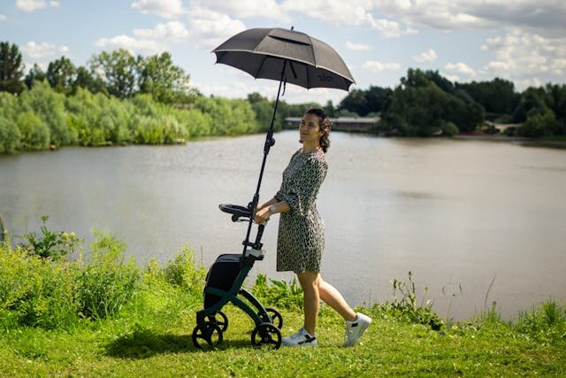 Молодая мама гуляет с прогулочной коляской у озера в солнечный день — лёгкая, компактная и удобная модель для города и путешествий.