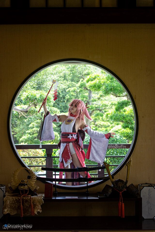    Прекрасная Яэ Мико на фоне зеленой листвы