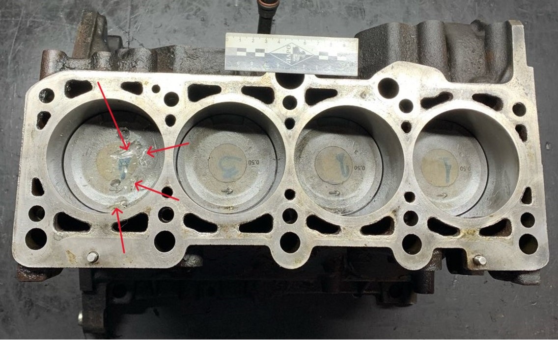 Фото 1. Шорт блок. Вид сверху. Повреждения днища поршня четвертого цилиндра показаны стрелками.