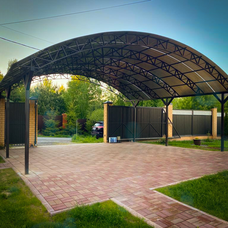 Навес для автомобиля из металла и поликарбоната, установленный во дворе частного дома. Прочная конструкция с камерной покраской (эпоксидный грунт, полиуретановая эмаль с отвердителем) защищает машину от солнца и осадков. Проект и монтаж — компания ARTZHELEZO.