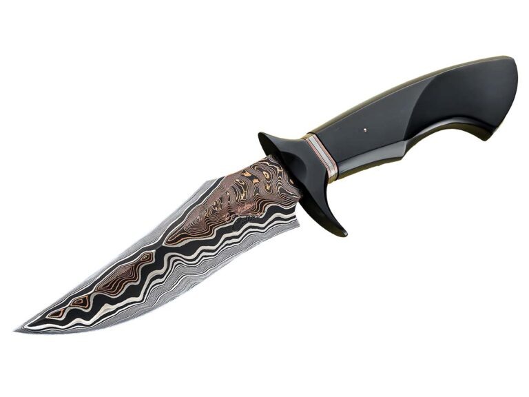 Нож от Дэна Томпкинса

Нож от Дэна Томпкинса, сделанный компанией Evolution Cutlery, имеет длинное лезвие длиной 5,75 дюймов. Это лезвие сделано из специальной стали, которую выплавляет компания Baker Forge & Tool. Нож имеет черную гарду и рукоятку, сделанную из материала Richlite. Медные вставки на ноже также сделаны компанией Baker. Весь нож вместе с лезвием имеет длину 11 дюймов.