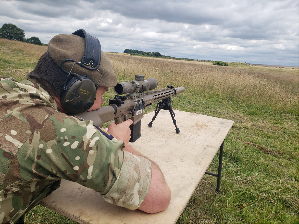 Британский солдат стреляет из “Sharpshooter” в калибре 6.5 Creedmoor с прицелом Leupold Mark 5HD 3.6-18x44 и саундмодератором Huxworks HXQB Helix на стрельбище COTEC во время проводившегося в 2022 г. в Шривенхеме симпозиума по ближнему бою.